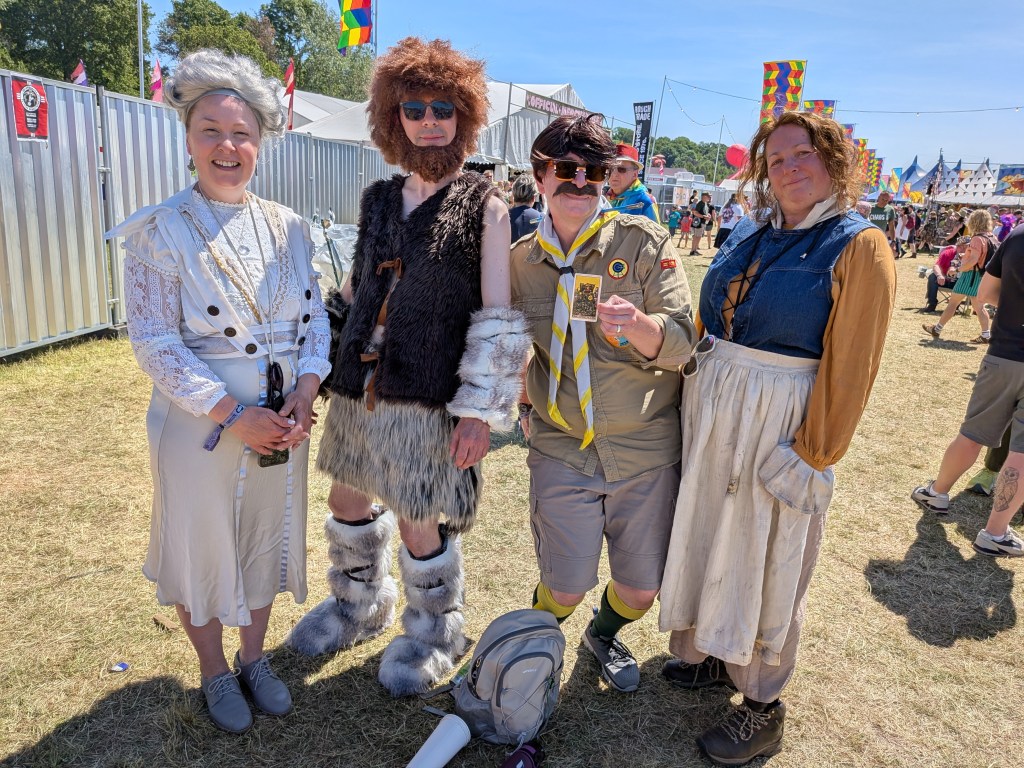 our Bearded Theory 2026 costume prize winners pose in BBC Ghosts-inspired outfits, with one holding a Rider-Waite-Smith tarot card.