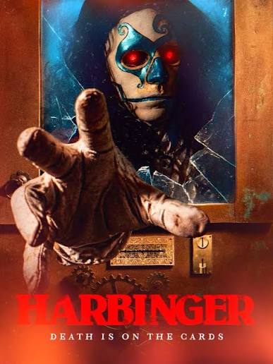 Movie poster for Harbinger featuring a sinister fortune-telling automaton with glowing red eyes and blue mask-like markings peering from behind a shattered glass window in a wooden cabinet. A large, textured hand reaches through the broken glass directly toward the viewer above a metal coin slot. The title "HARBINGER" is displayed in large red font at the bottom, accompanied by the tagline "DEATH IS ON THE CARDS".